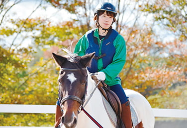 写真：蒜山ホースパーク研修の様子。馬に乗っている女子学生。