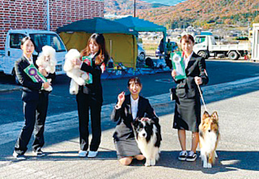 写真：ハンドラー昇格試験&競技会の様子。犬を台の上に載せている学生。