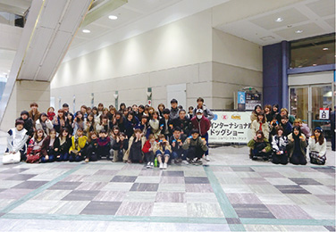 写真:JKC本部トリミング競技会の様子。台の上に乗った3匹の犬とトリミングをする3人の学生。