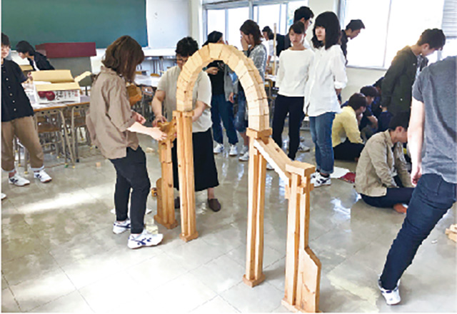 写真:木材の枠組みをハンマーではめ込み組み立てている様子