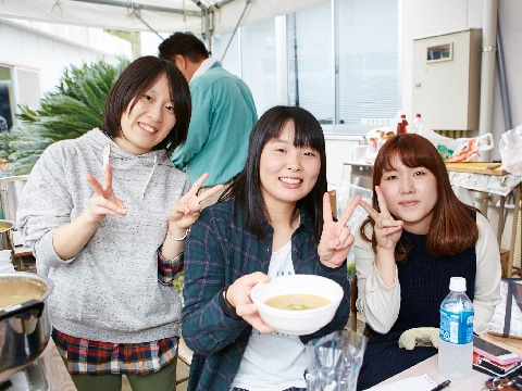 模擬店の出し物を手にした３人の女子学生