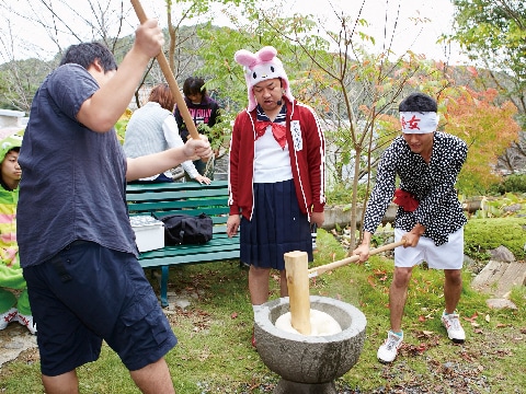 餅つきをする３人の男子学生